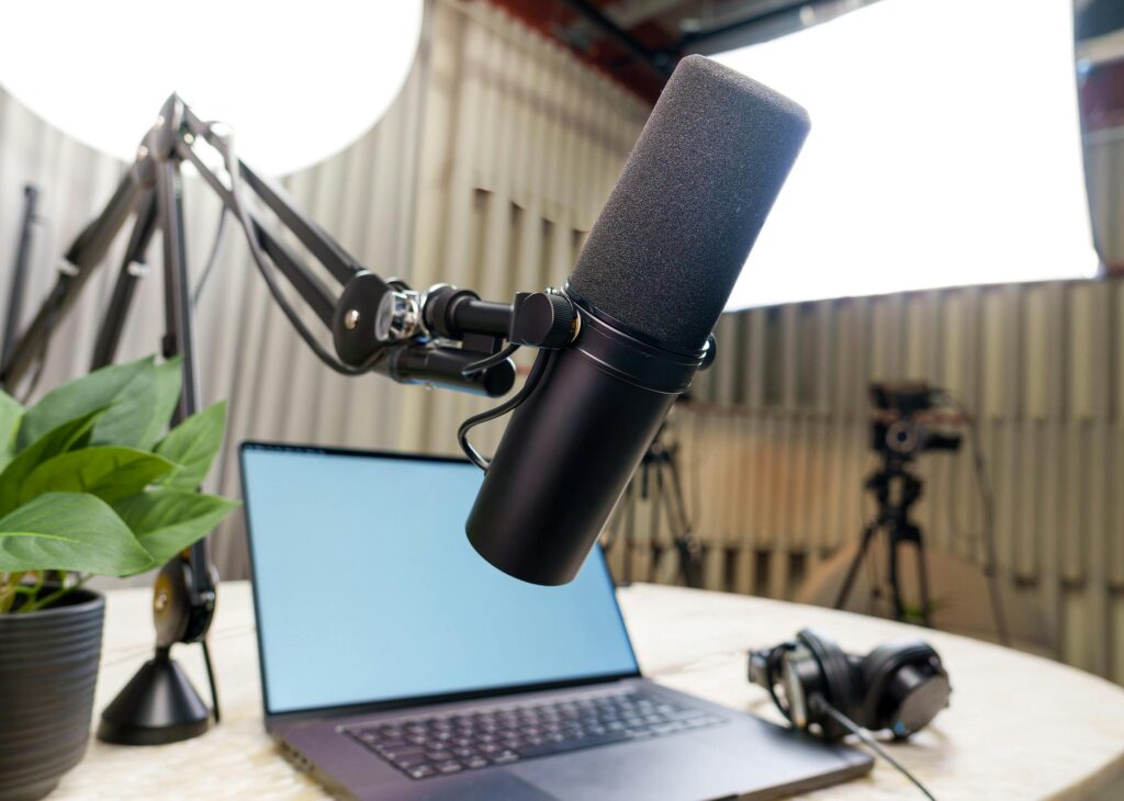 Professional podcast studio setup featuring a microphone, laptop, and headphones ready for recording.